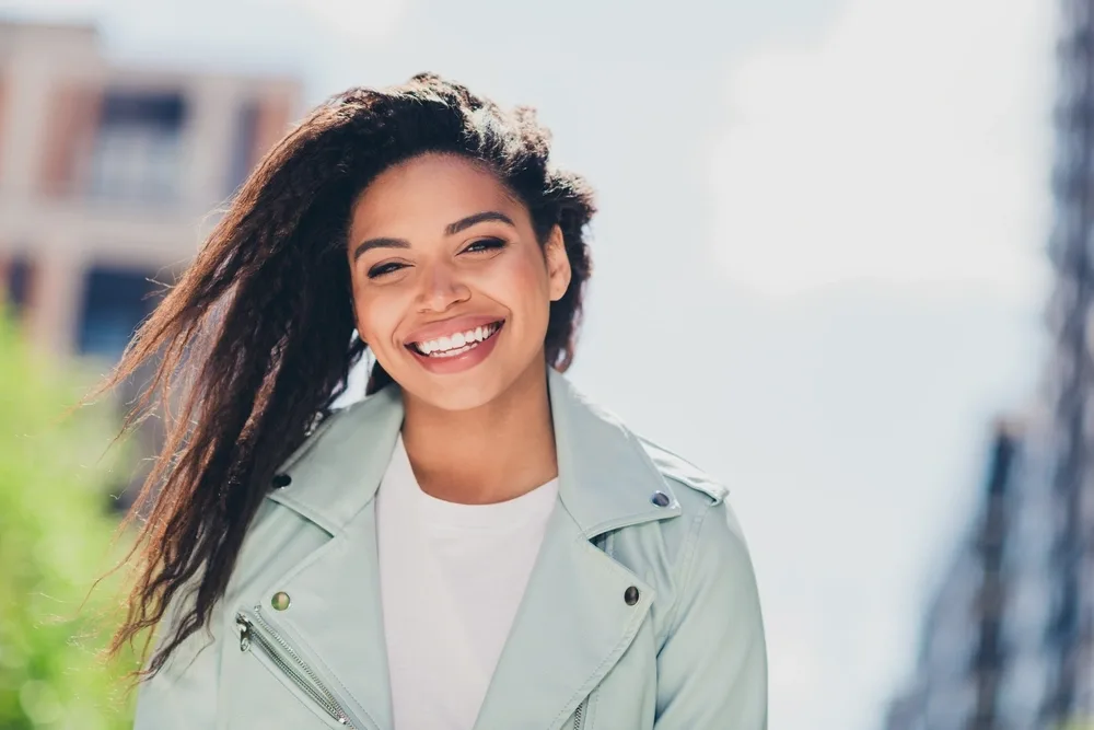 Smiling woman in a light jacket outdoors
