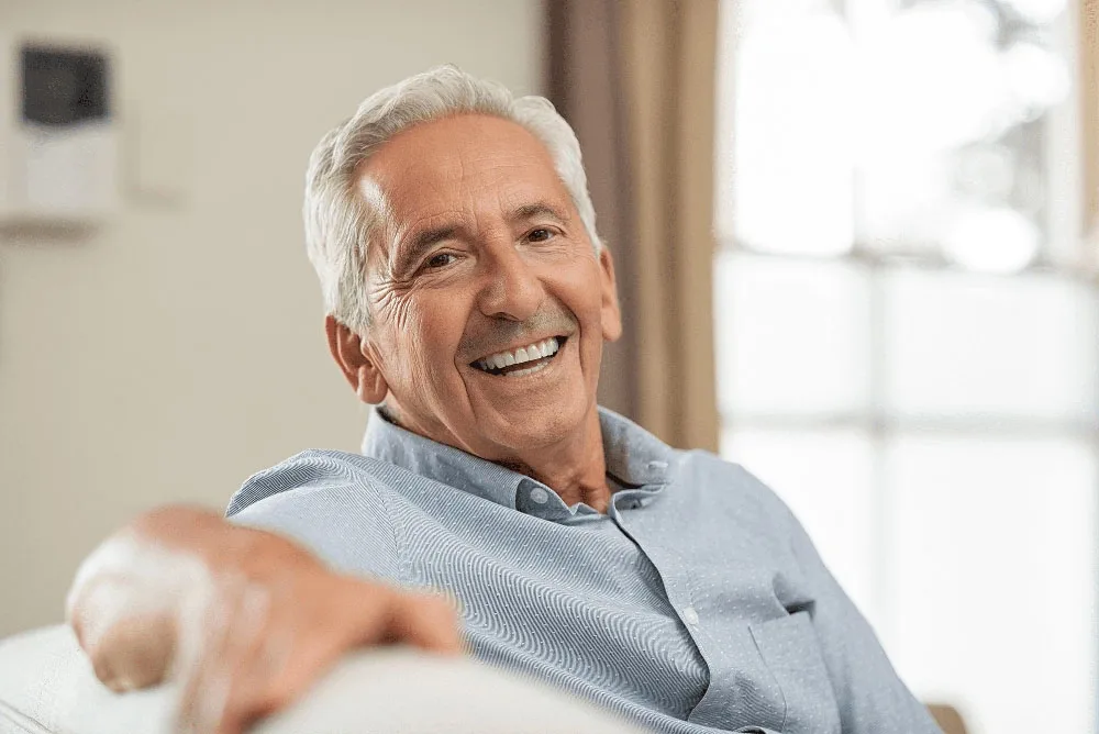 Smiling older man gesturing while talking indoors
