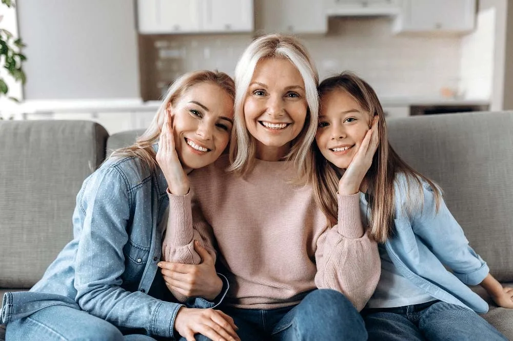 Three generations of women sitting together on a couch, smiling