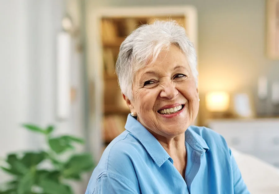 Smiling older woman in a blue cardigan indoors